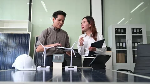 Two Asian engineers collaborate on a solar and wind energy project, discuss.. Stock Footage 313266312