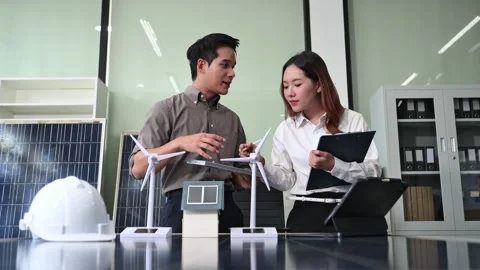 Two Asian engineers collaborate on a solar and wind energy project, discuss.. Stock Footage 313266316