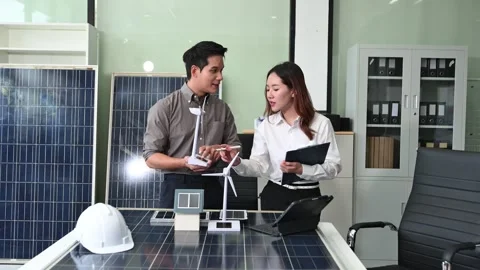 Two Asian engineers collaborate on a solar and wind energy project, discuss.. Stock Footage 313266414