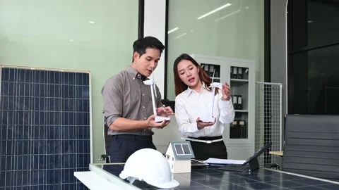 Two Asian engineers collaborate on a solar and wind energy project, discuss.. Stock Footage 313266415