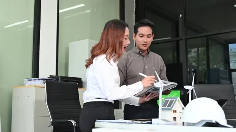 Two Asian engineers collaborate on a solar and wind energy project, discuss.. Stock Footage 313266552