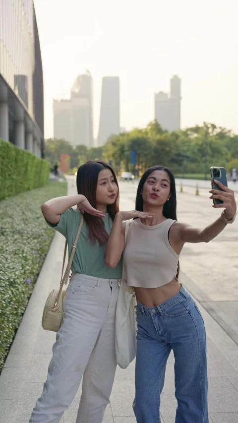 Two Asian friends taking a selfie in a Bangkok urban park Stock Footage 293107082