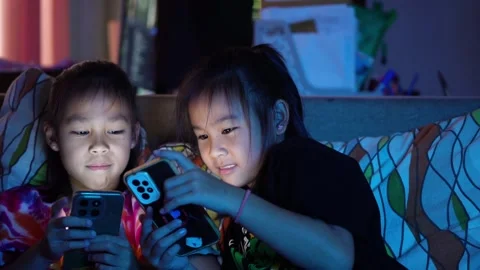Two Asian girl using smartphone in bed at night, screen light on face Stock Footage 314308532