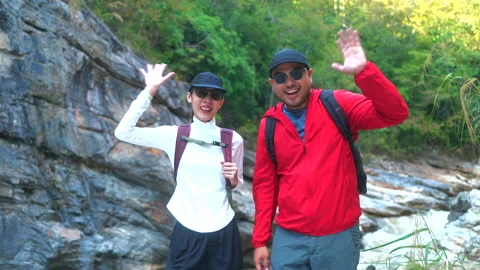 Two asian hiker stands on a light colored rock beside a gentle flowing stream 스톡 동영상 342410020