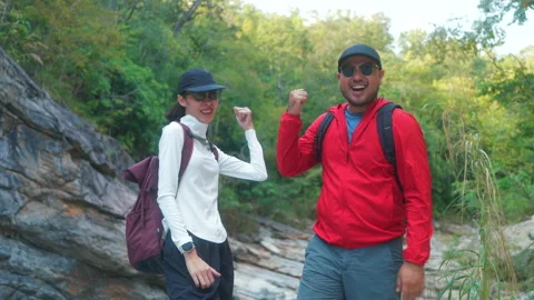 Two asian hiker stands on a light colored rock beside a gentle flowing stream Vídeo Stock 342410083