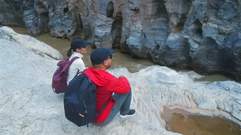 Two asian hiker stands on a light colored rock beside a gentle flowing stream Stock-Footage 342410270