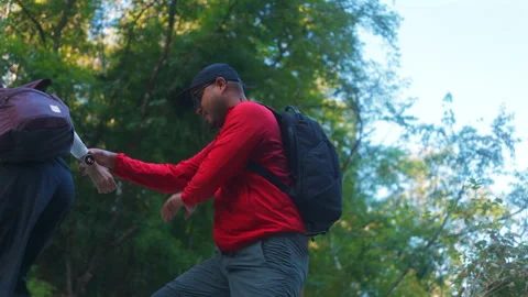Two asian hiker stands on a light colored rock beside a gentle flowing stream Vídeo Stock 342410472