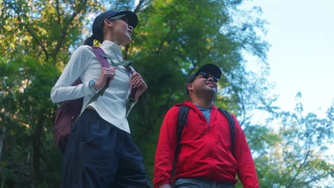 Two asian hiker stands on a light colored rock beside a gentle flowing stream Video stock 342410598