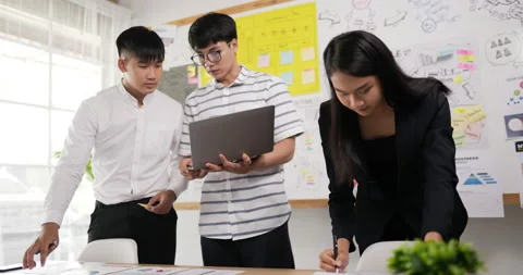 Two asian men and one woman checking to task on workplace desk while standing Stock Footage 201916828