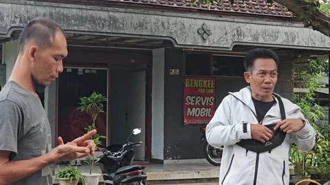 Two Asian Men Talking Casually Outside A Local Auto Repair Shop Vídeos de archivo 345327678