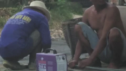 Two Asian Men Working Outdoors Welding A Metal Bar With Sparks Flying Stock Footage 340078969