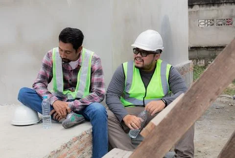 Two Asian or Indian builder workers wearing safety reflected vests and helm.. Stock Photos