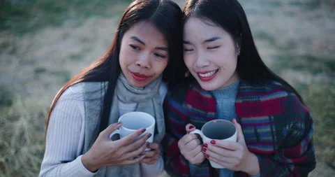Two Asian siblings sit and enjoy the morning view and the cold atmosphere. Stock Footage 323787950