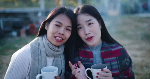 Two Asian siblings sit and enjoy the morning view and the cold atmosphere. Stock Footage 323787967