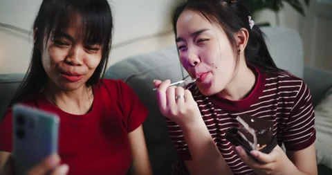 Two Asian siblings sit on a sofa and use cell phone to talk to friends Stock-Footage 305217236