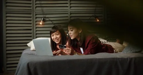 Two asian sisters spending time together, having online shopping, chatting and Stock-Footage 117331884