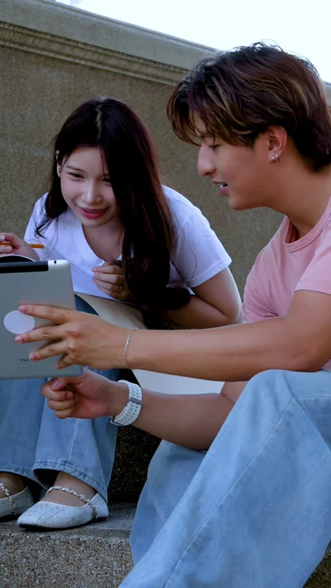 Two Asian University Students Collaborating with Digital Tablet on Campus Steps Stock Footage 335500500