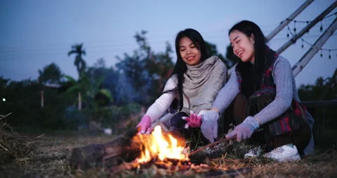 Two Asian women sit by a fire on a cold morning. Winter weekend activities Stock-Footage 318502053