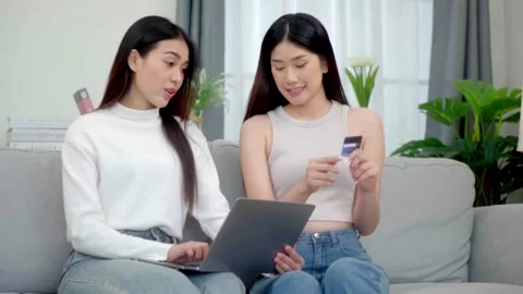 Two asian women  using online shopping credit cards via their laptops on so.. Stock Footage 244974591