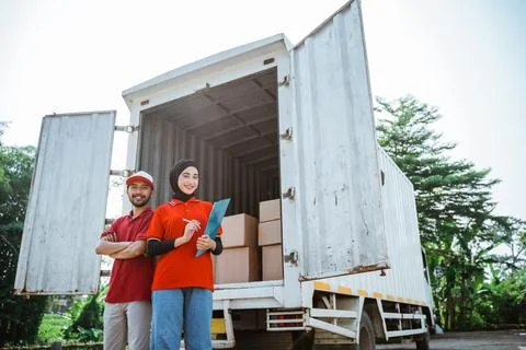 Two asian workers standing behind a logistics container truck Stock Photos