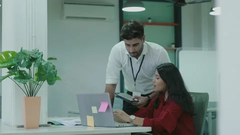 Two Asian workers talking in office young Indian colleagues discussing work. Видео 163403012
