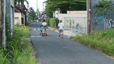Two Asians walking on an asphalt road on a sunny morning Stock Footage 229448996
