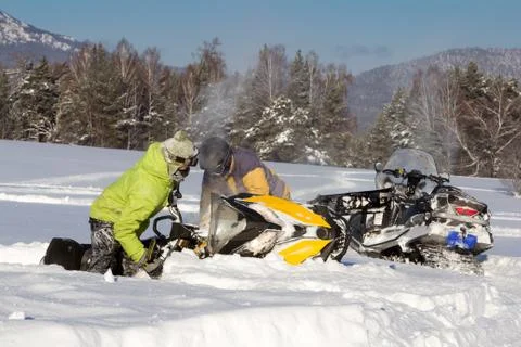 Two athletes pull a snowmobile. Stock Photos