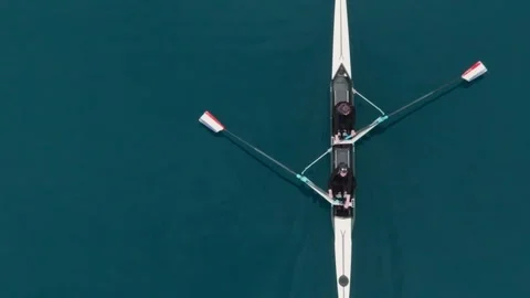 Two athletes rowing a sculling boat on calm blue water, teamwork and endurance Stock Footage 317023608
