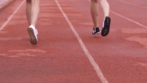 Two athletes run on a treadmill at the stadium. Bottom view, feet in the frame. Stock-Footage 99157088