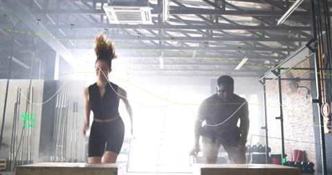 Two athletes squatting and exploding into box jumps for gym training, motion Stock Footage 334176048