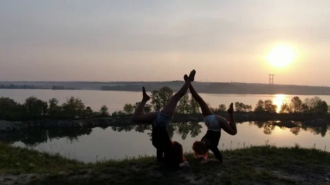Two athletic girls are doing forearm handstand early in the morning near a river Stock Footage 111712178