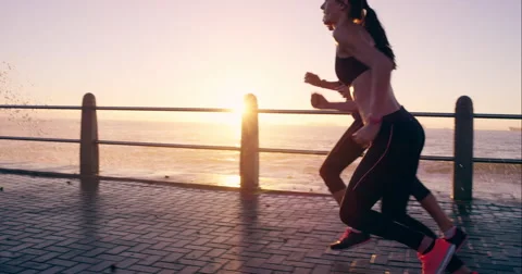 Two athletic women running outdoors slow motion on promenade at sunset Stock Footage