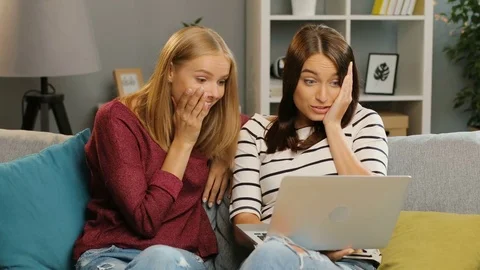 Two attaractive young women looking at the laptop screen and wondering on the Stock Footage 81926739