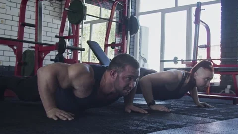 Two Attractive Athletic bodybuilders man and woman does Push-up exercise at gym Stock Footage 143518261