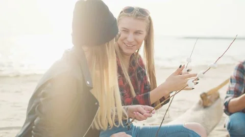 Two attractive blondes string marshmallows on twigs and laugh close-up Stock Footage 75691952