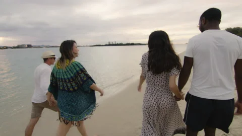 Two attractive couples, holding hands, walking on the beach, talking and smiling Stock Footage 199457482