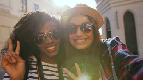 Two attractive friends grimacing and taking selfie on mobile camera  on sunny da Stock Footage 81831227