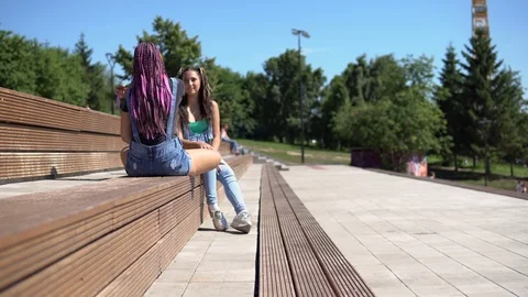 Two attractive girlfriends talking to each other having a good mood sitting on a Stock Footage 92112643