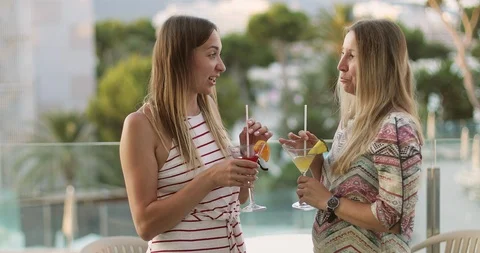 Two attractive women are talking and drinking cocktail in the background of the Stock Footage 103252572