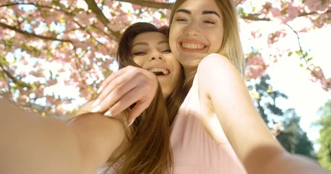 Two attractive young blonde and brunette girl friends are hugging and smiling Stock Footage 89181726