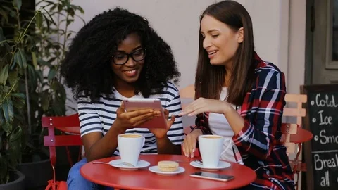 Two attractive young friends sitting together on terrace in cafe and talking Stock Footage 81834972