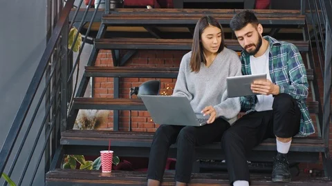 Two attractive young office workers analyzing the plan of work using the Stock Footage