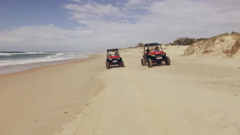 Two ATV vehicles racing on a beautiful beach with ocean and open sky in the back Stock Footage 199455486