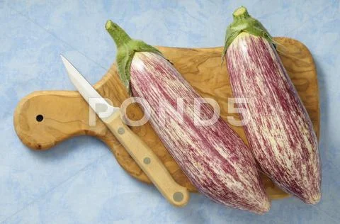 Two aubergines on a chopping board with a knife Stock-Fotos