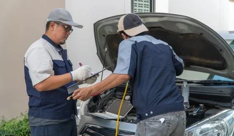 Two Auto repairman checks the engine and cooling system before traveling on a Foto stock