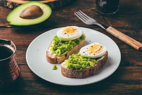 Two avocado toasts with boiled egg Stock Photos