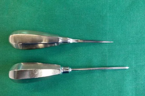 Two awls of different sizes lie on a green surgical drape Stock Photos