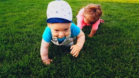 Two babies crawling on the bright green grass on a warm summer day Stock Footage 110805022