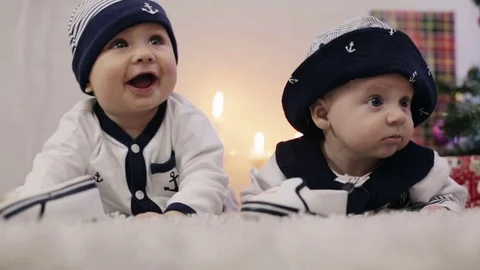 Two babies dressed as sailors lie on his stomach looking around Stock Footage 69929904