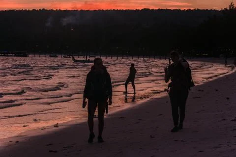 Two Backpacker walking on the beach at sunset Stock Photos